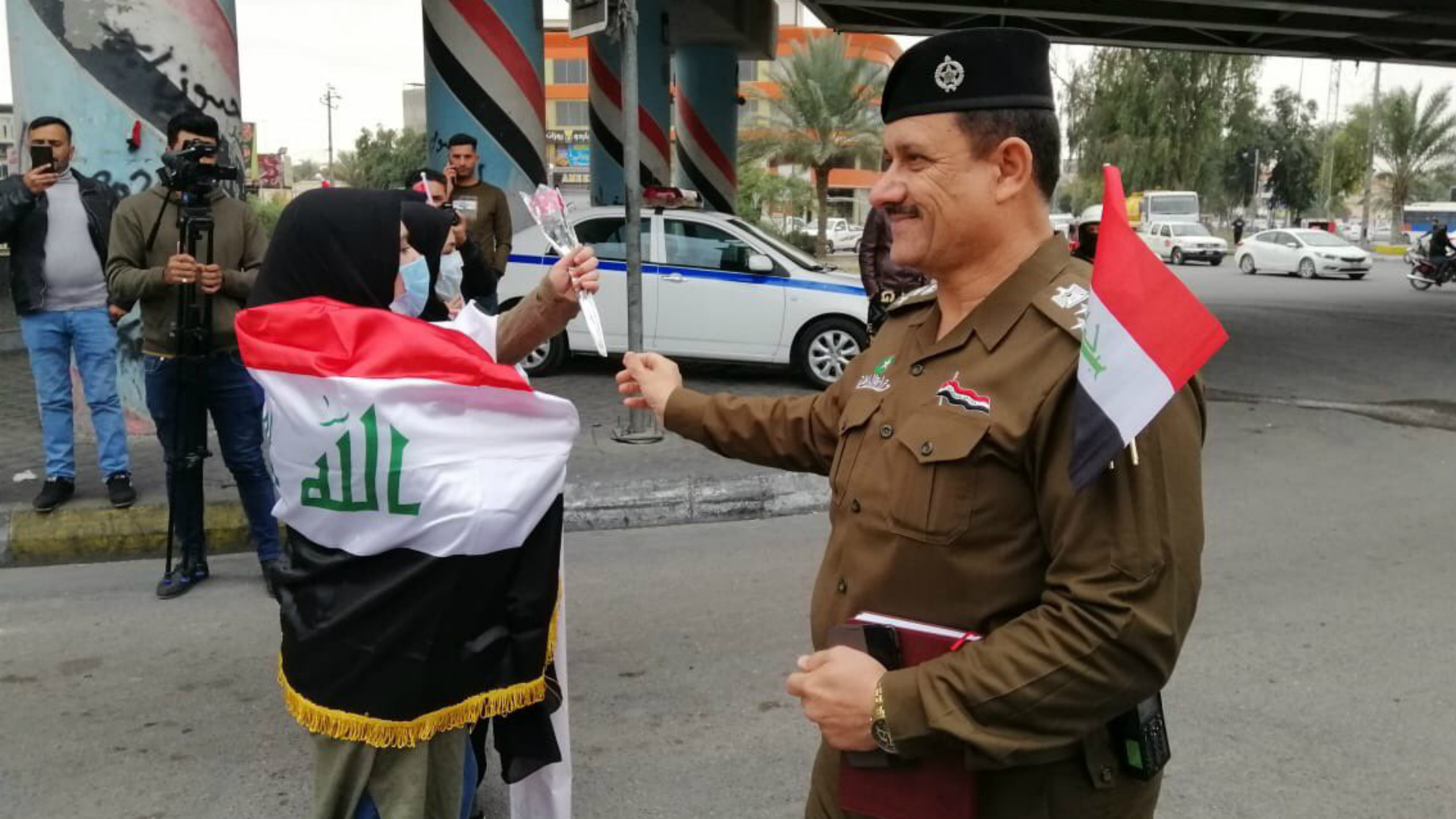 القوات الأمنية توزع الورد والأعلام على المتظاهرين في كربلاء